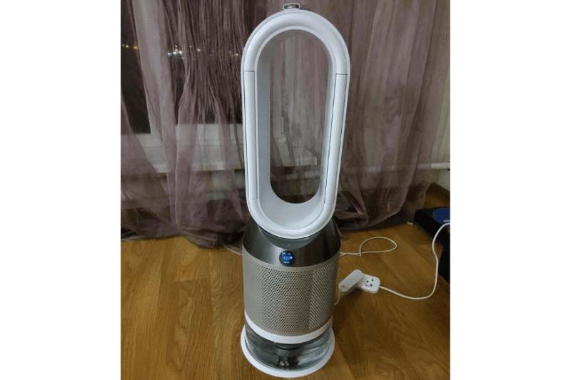 Der Dyson Pure Humidify + Cool PH01 Luftreiniger, Ventilator und Luftbefeuchtung steht auf dem Boden vor einem Fenster